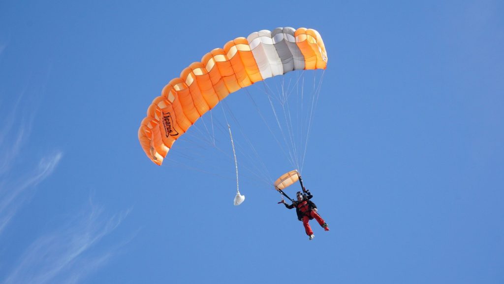 Fallschirmspringer mit orangenem Fallschirm